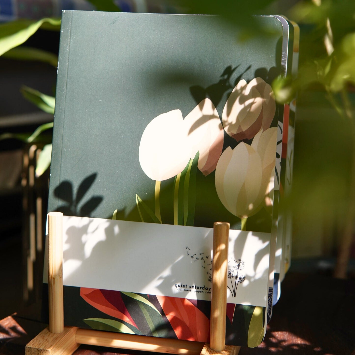 Floral notebook on a stand with plants in the background