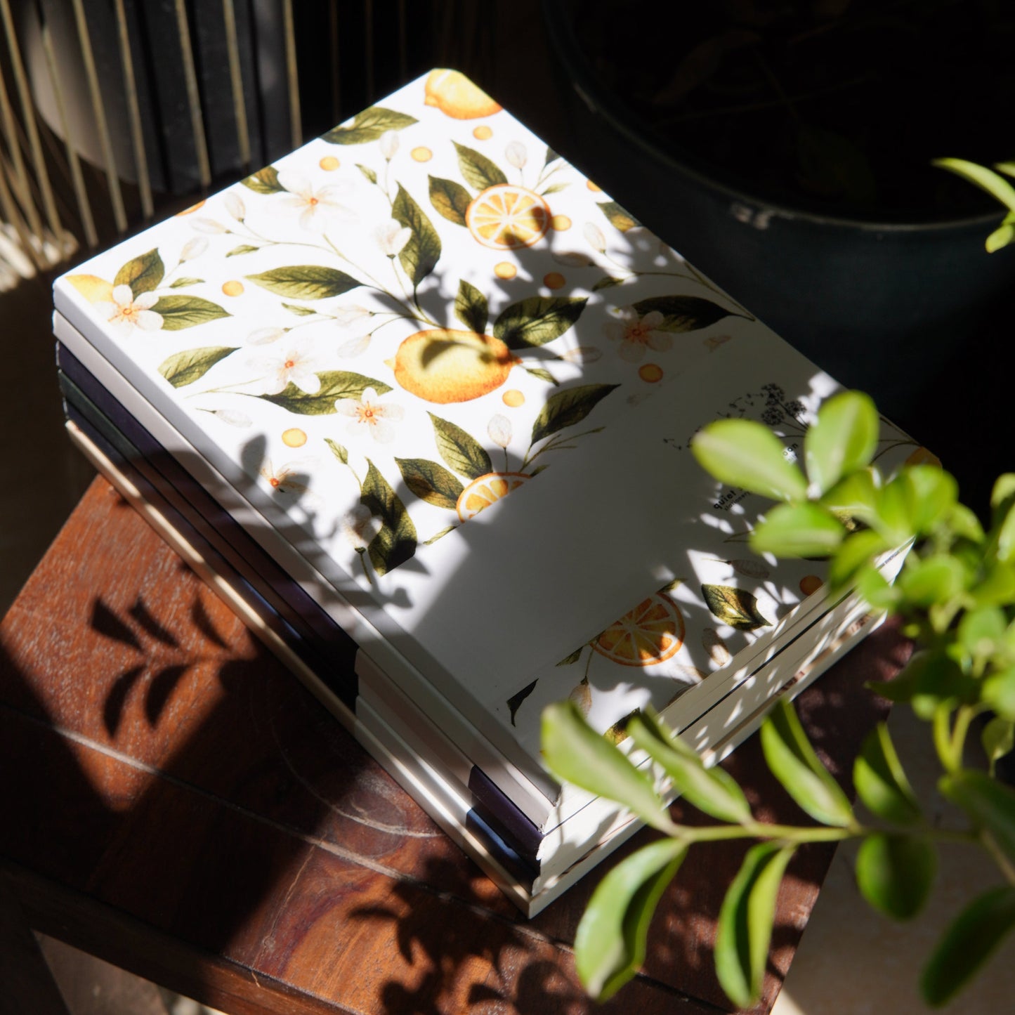 Floral notebook on a wooden surface with leaves in the background